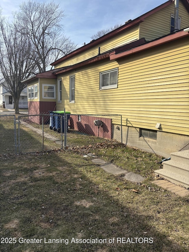 view of side of home featuring fence and a lawn