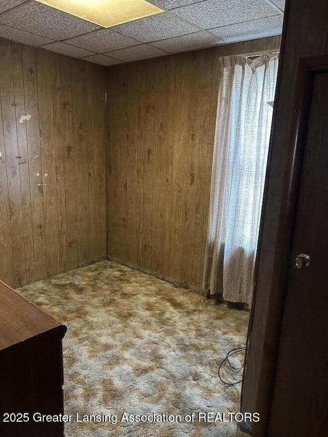 empty room with wooden walls and a paneled ceiling