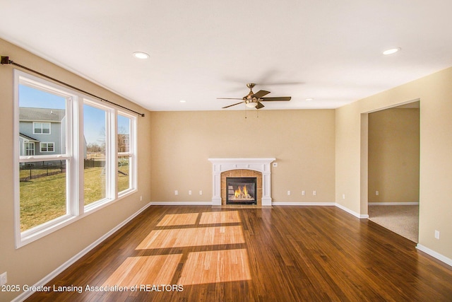 unfurnished living room featuring a tiled fireplace, wood finished floors, recessed lighting, baseboards, and ceiling fan