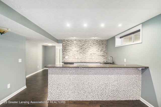 bar with dark wood-type flooring, recessed lighting, baseboards, and a sink