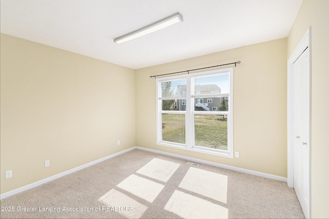 carpeted empty room featuring visible vents and baseboards