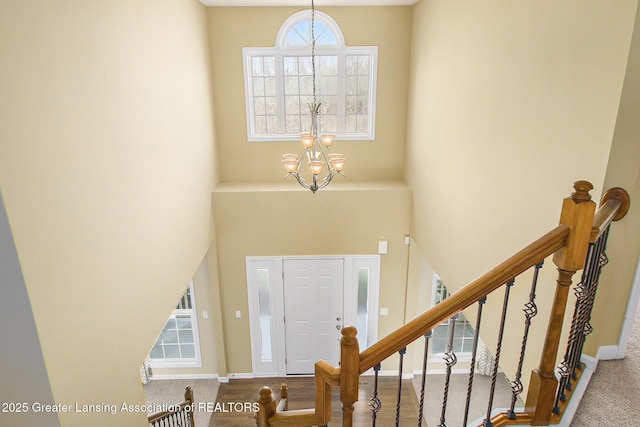 entrance foyer with baseboards, a notable chandelier, a high ceiling, and stairs