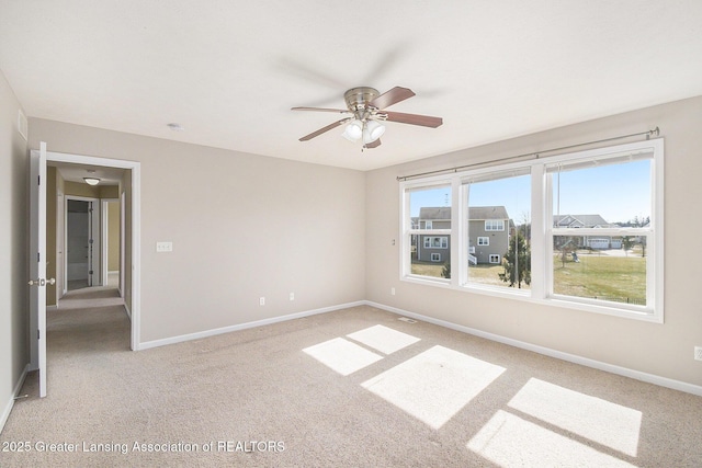 unfurnished room with a ceiling fan, baseboards, and light carpet