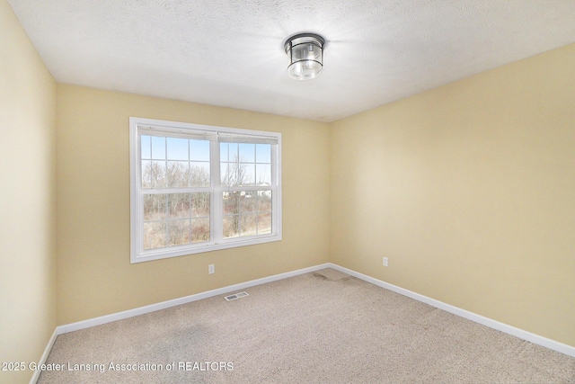 carpeted spare room featuring baseboards, visible vents, and a textured ceiling