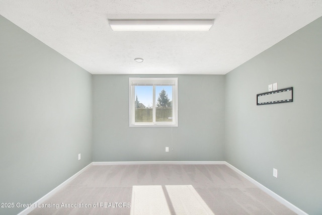 unfurnished room featuring light carpet, baseboards, and a textured ceiling