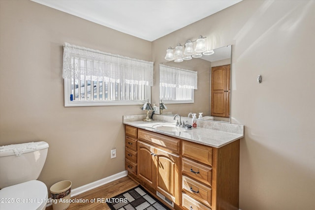 bathroom with baseboards, toilet, wood finished floors, and vanity