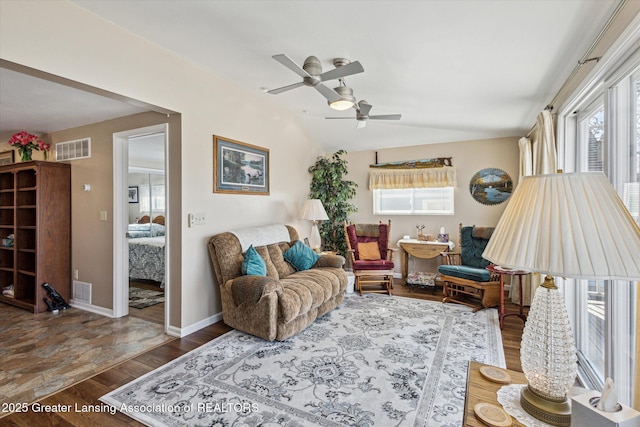 living area featuring visible vents, baseboards, ceiling fan, vaulted ceiling, and wood finished floors