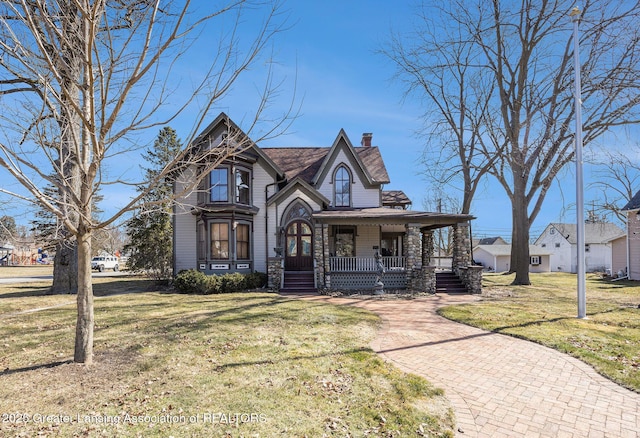 view of front of property with a front yard, covered porch, and a chimney