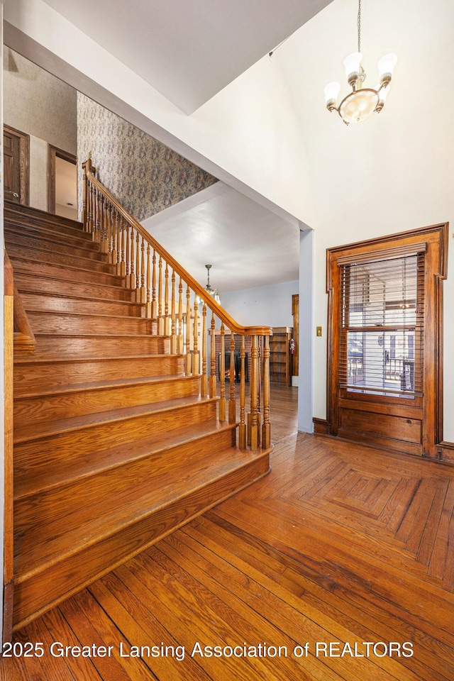 foyer entrance with parquet floors, a chandelier, and stairs