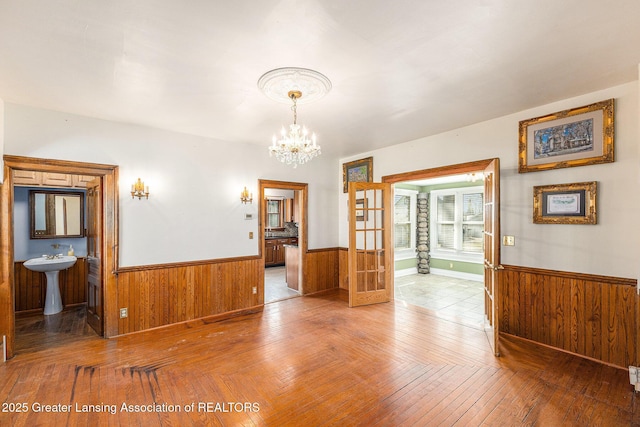 unfurnished room featuring a sink, a chandelier, wainscoting, and wood walls