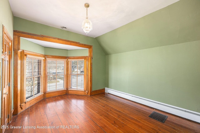 additional living space featuring visible vents, hardwood / wood-style flooring, lofted ceiling, baseboard heating, and a chandelier