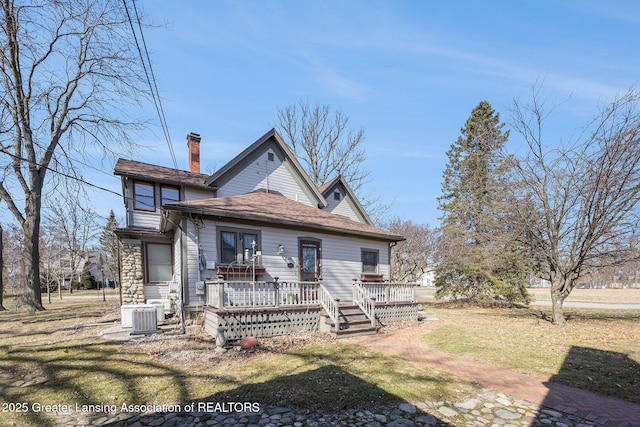 view of front of property featuring a deck, a front lawn, cooling unit, and a chimney