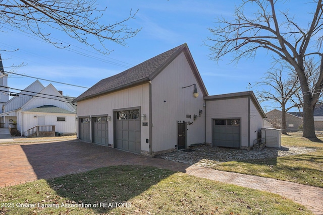view of side of home featuring decorative driveway and an attached garage