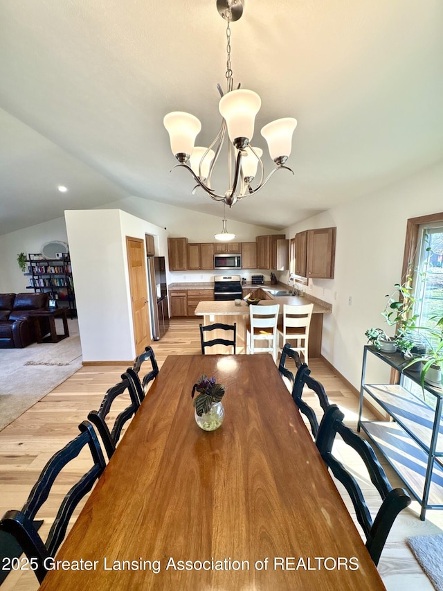 dining space featuring light wood-type flooring, lofted ceiling, and an inviting chandelier