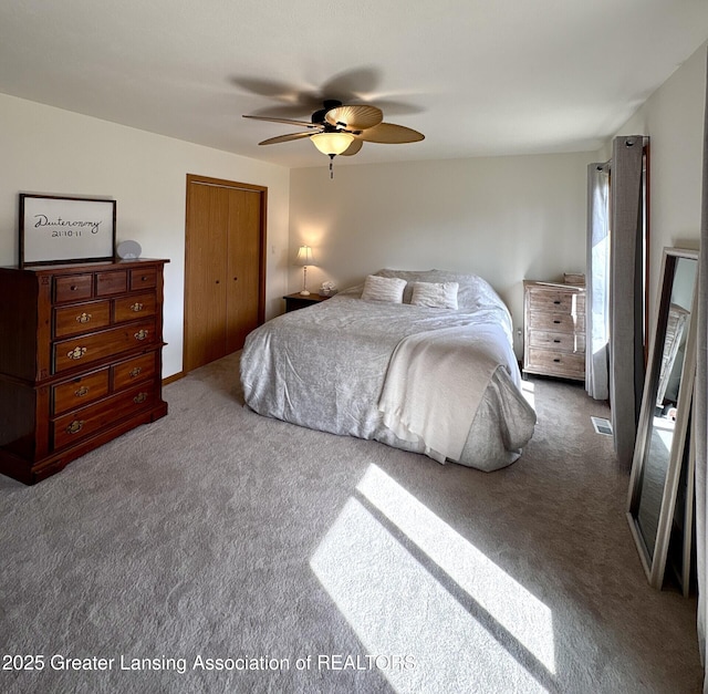 carpeted bedroom featuring a ceiling fan, visible vents, and a closet