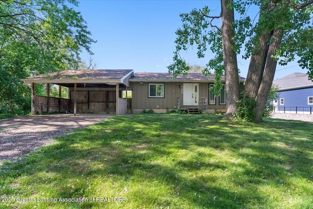 view of front of home featuring an attached carport, fence, driveway, entry steps, and a front lawn