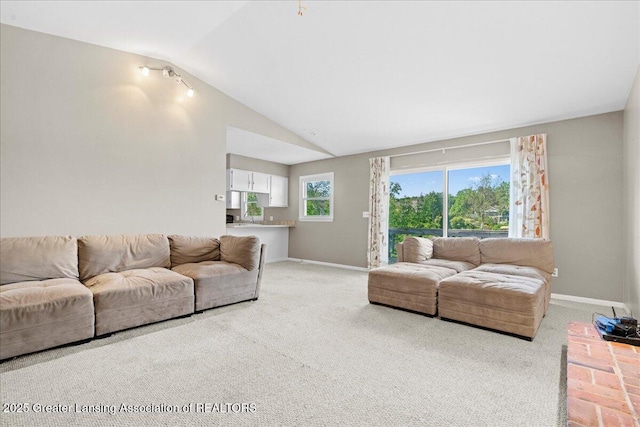 living area with light colored carpet, lofted ceiling, plenty of natural light, and baseboards