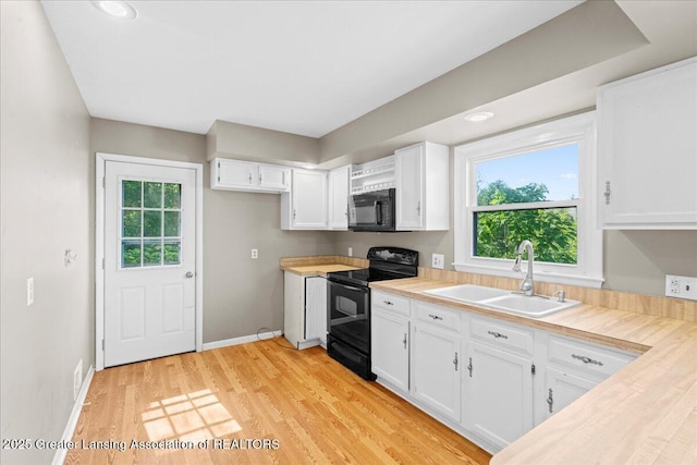 kitchen with white cabinetry, black appliances, light countertops, and a sink