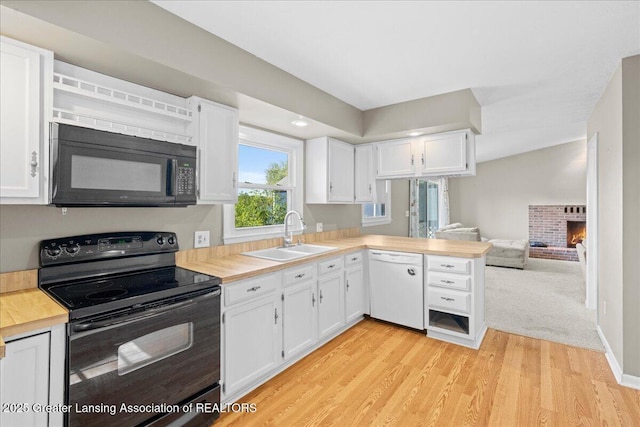 kitchen featuring a sink, white cabinetry, black appliances, and light countertops