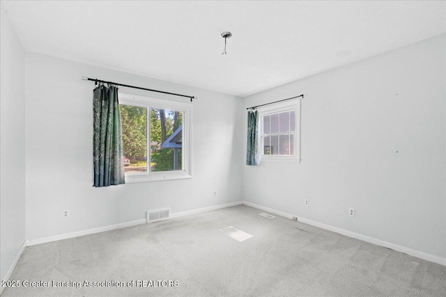 carpeted spare room featuring baseboards and visible vents