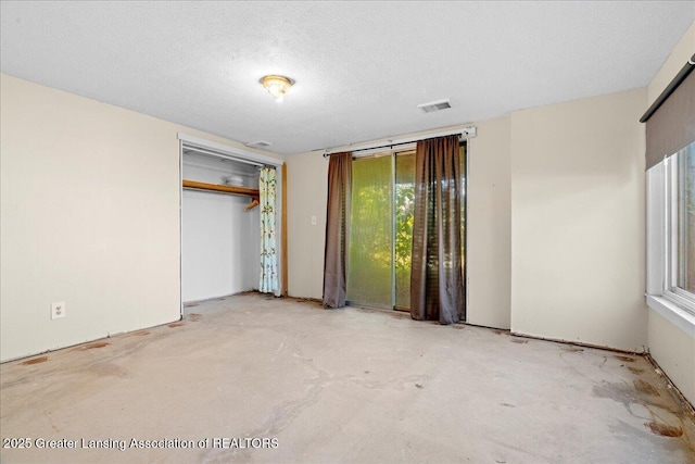 unfurnished bedroom with unfinished concrete flooring, visible vents, a closet, and a textured ceiling