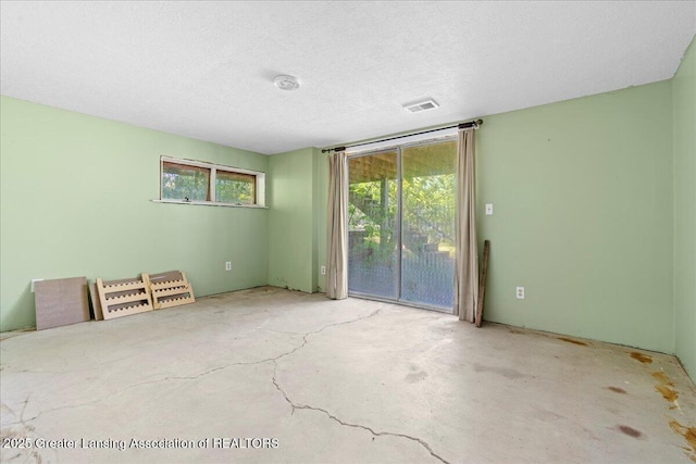 empty room featuring visible vents, a textured ceiling, and unfinished concrete flooring