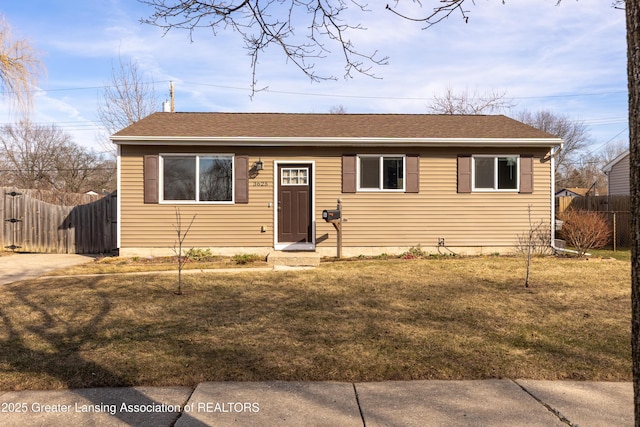 view of front of property with a shingled roof, a front yard, and fence