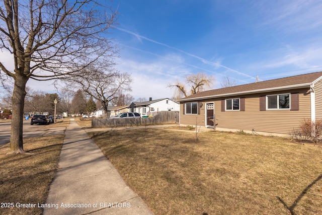 exterior space with fence, a lawn, and roof with shingles