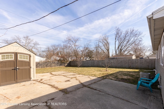 view of yard featuring an outbuilding, a fenced backyard, a storage shed, and a patio area