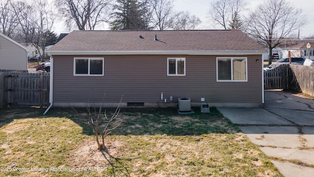 rear view of house with a lawn, central AC, a fenced backyard, and a shingled roof