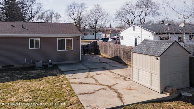 back of house with an outbuilding, central AC unit, fence, a storage shed, and a residential view