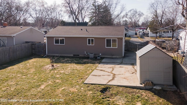 back of house with a lawn, a fenced backyard, and a storage shed