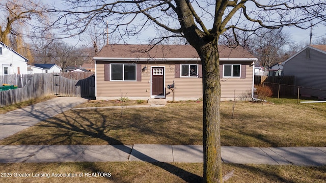 bungalow-style house featuring a front lawn, fence, and driveway