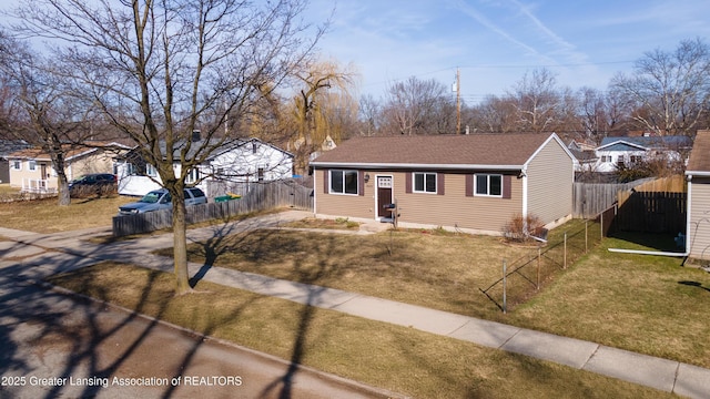 view of front of home featuring a front yard, fence, driveway, and a shingled roof