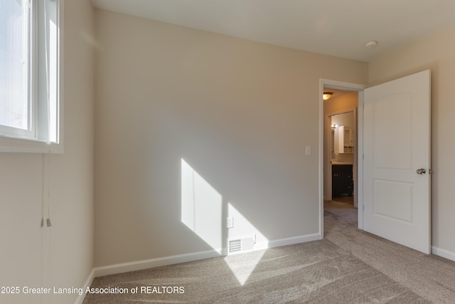 carpeted spare room with baseboards and visible vents