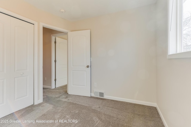 unfurnished bedroom with a closet, visible vents, baseboards, and carpet