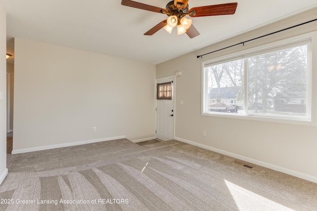 spare room featuring light carpet, baseboards, visible vents, and ceiling fan