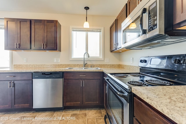 kitchen with a sink, dark brown cabinets, appliances with stainless steel finishes, and light countertops