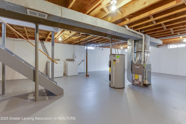 basement featuring heating unit, visible vents, washing machine and dryer, and electric water heater