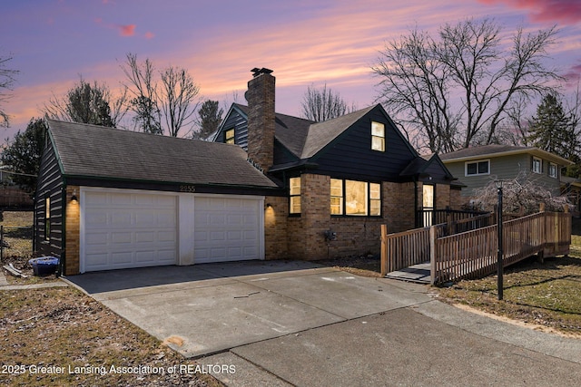 view of front of home featuring roof with shingles, concrete driveway, a garage, brick siding, and a chimney