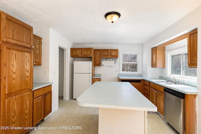 kitchen with a kitchen island, dishwasher, brown cabinets, freestanding refrigerator, and a sink