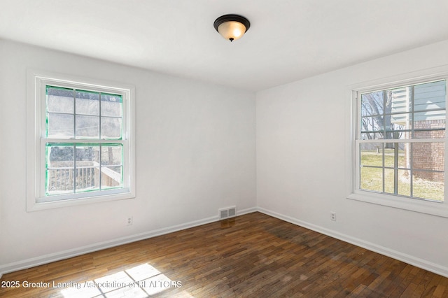 empty room with baseboards, visible vents, and wood-type flooring