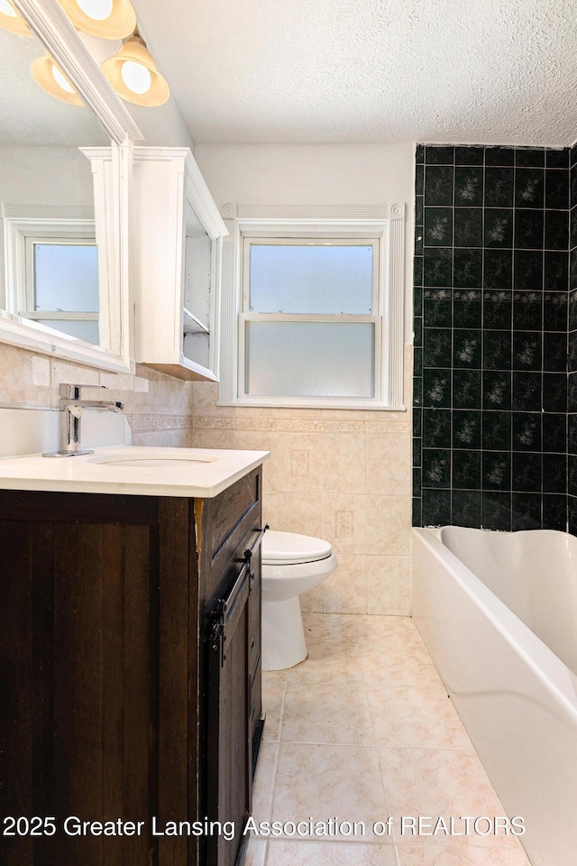 bathroom with toilet, a textured ceiling, tile walls, a bath, and vanity