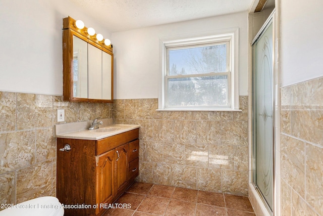 bathroom with tile walls, toilet, an enclosed shower, a textured ceiling, and vanity