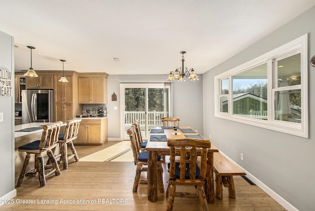 dining space featuring a wealth of natural light, a notable chandelier, light wood-type flooring, and baseboards