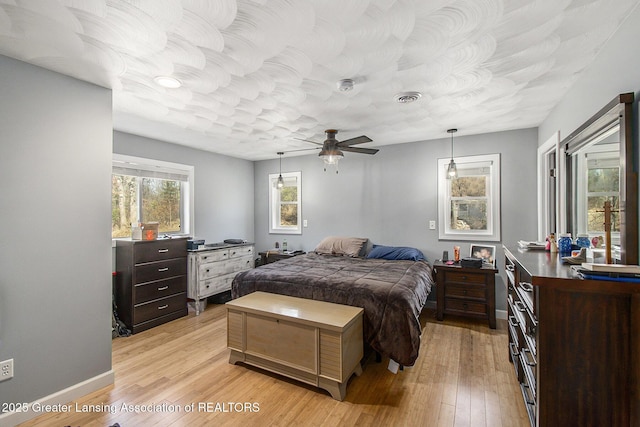 bedroom with light wood-type flooring, visible vents, baseboards, and a ceiling fan