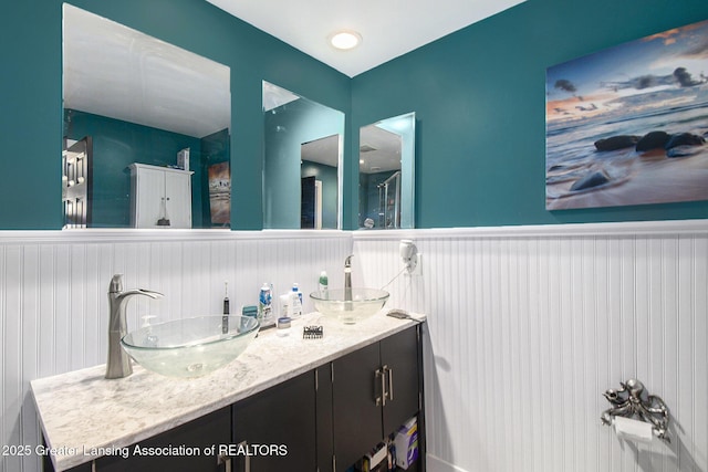 bathroom with double vanity, a wainscoted wall, and a sink