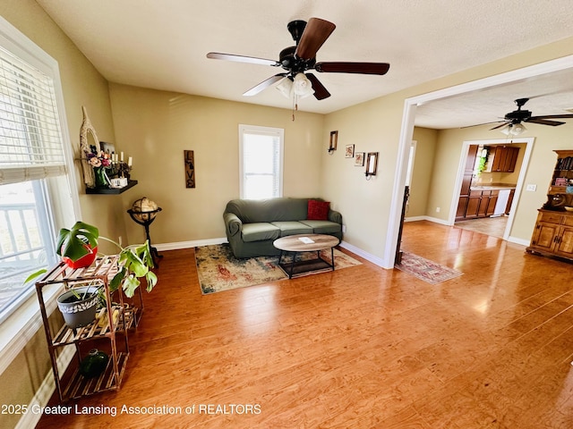 living area with wood finished floors, baseboards, and ceiling fan