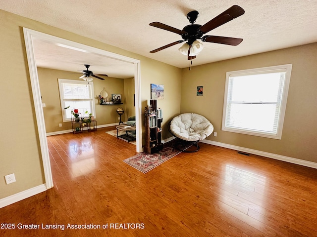 unfurnished room with a ceiling fan, wood finished floors, and visible vents