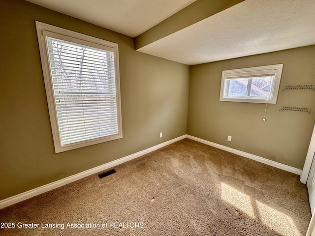 unfurnished room featuring carpet flooring, visible vents, and baseboards